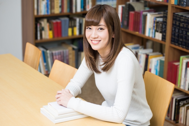 図書館で勉強している笑顔の女子大生