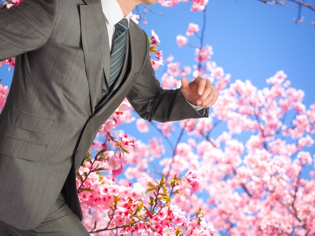 桜を背景にスーツで走る男性